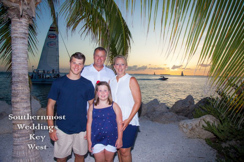 Family poses for photos in front of the sunset