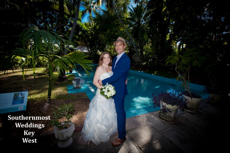 Wedding couple poses for photos infront of the pool on the grounds of the Hemingway House & Museum