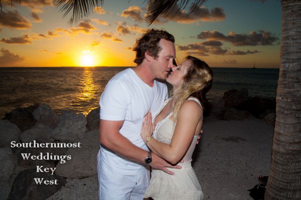 Couple kissing with the sunset in the background - Image by Southernmost Weddings