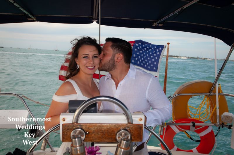 Wedding couple steering the sailboat after their wedding by Southernmost Weddings Key West