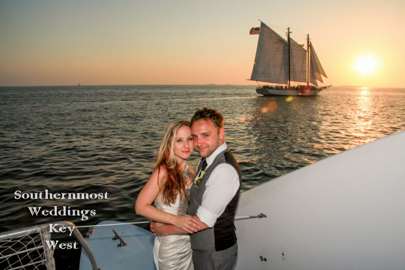 Wedding Couple poses for photos on a sailboat with the sunset setting in the background