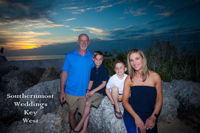 Family poses for photos in front of the sunset