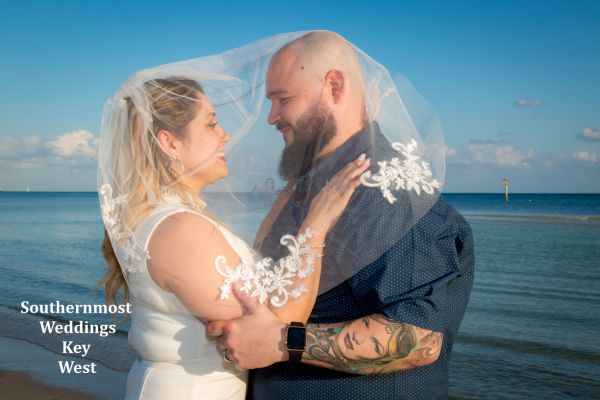 Wedding couple poses for photos on Smathers Beach in Key West, FL.