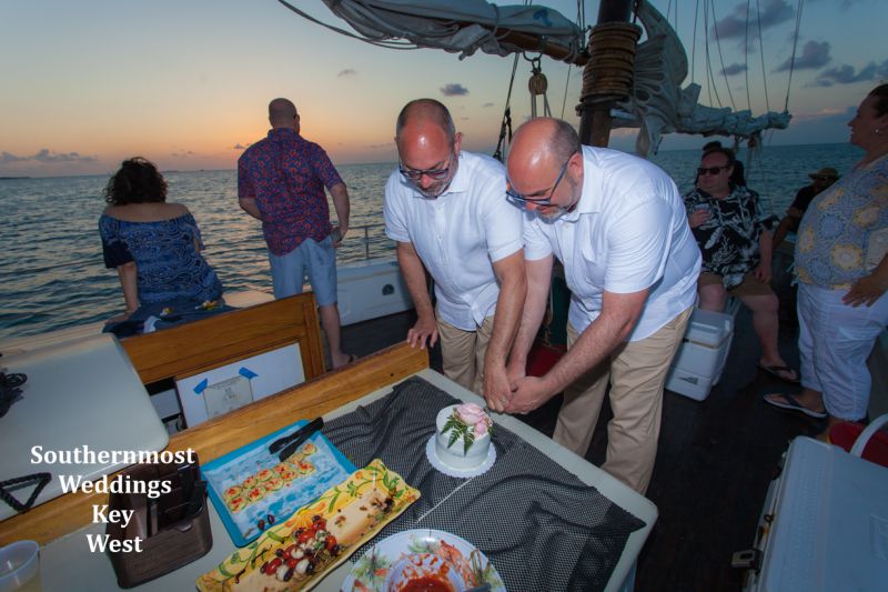 Wedding couple cut the wedding cake during their private sunset sail reception off the coast of Key West, Florida