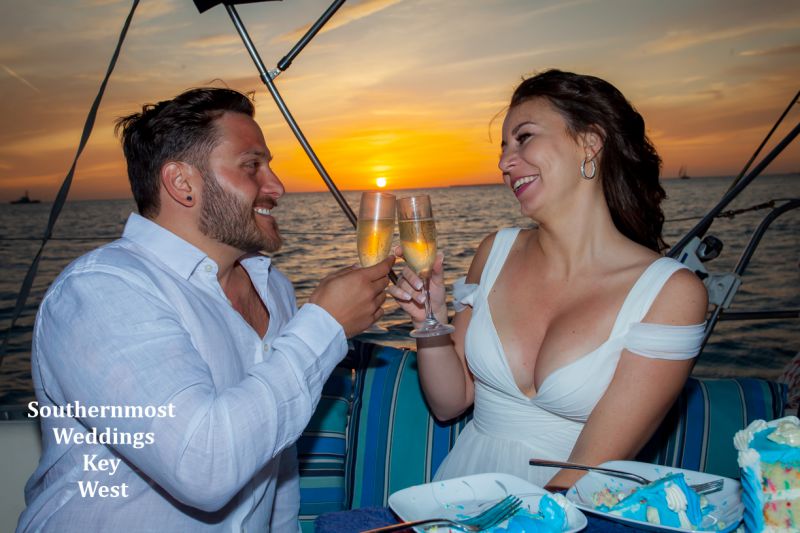 Wedding couple celebrate their wedding on the Gulf of Mexico with a champagne toast at sunset