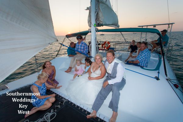 Wedding couple relax on the bow of their private catamaran sunset sail during their reception by Southernmost Weddings