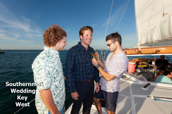 Groomsmen pose for photos during a private sunset sailboat wedding by Southernmost Weddings