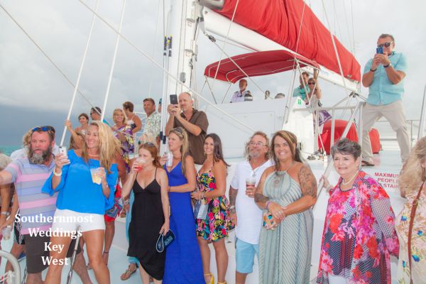Wedding party pose for photos during their private sunset sailboat reception planned by Southernmost Weddings Key West