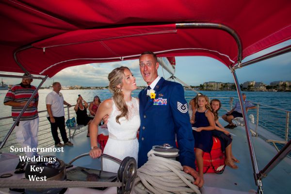 Wedding couple steering the sailboat during their private sunset sail wedding cruise planned by Southernmost Weddings Key West