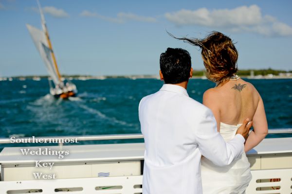 Bride & Groom pose for photos in front of an old-fashioned historic Schooner after their wedding by Southernmost Weddings Key West