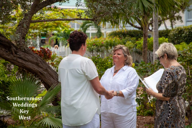 Two women say their wedding vows in the Truman Annex Butterfly Garden during a ceremony by Southernmost Weddings