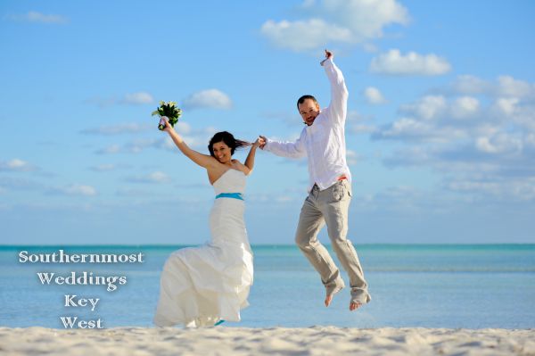 Wedding Couple jumping to celebrate their marriage on Smathers Beach in Key West, Florida
